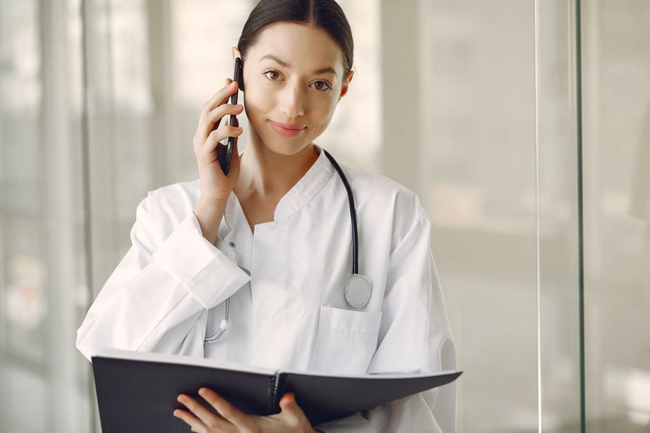 A physician in a white coat standing in a clinical consulting room