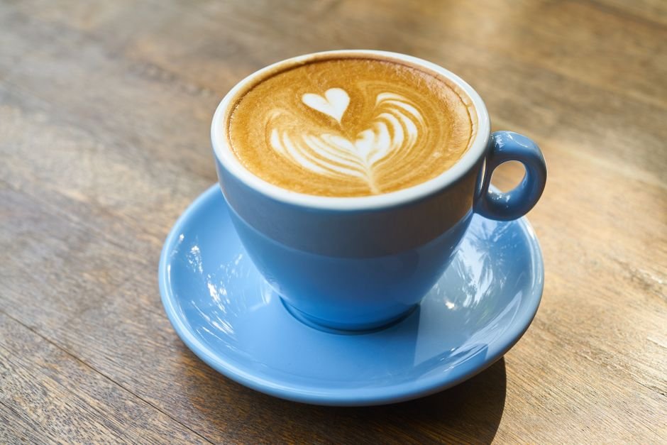 A cup of black coffee on a table beside a window