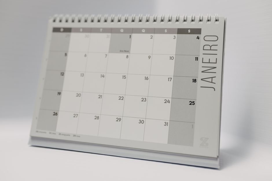 A wall calendar with days marked, photographed on a desk