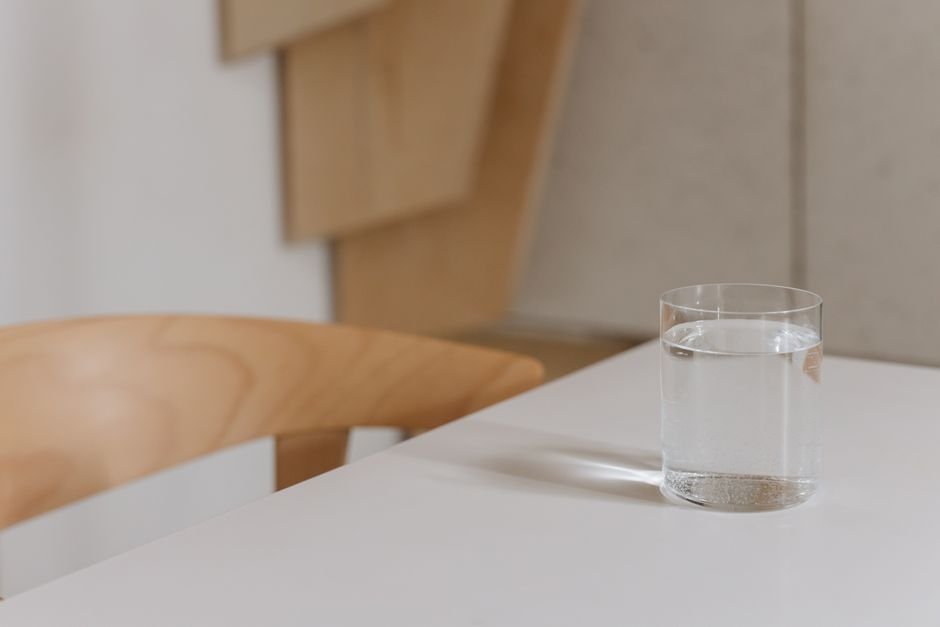 A glass of water on a wooden table in daylight