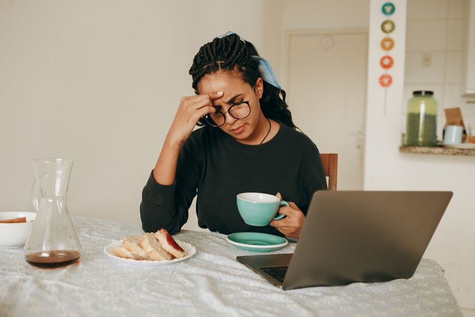 A woman resting the palm of her hand across her forehead at a desk
