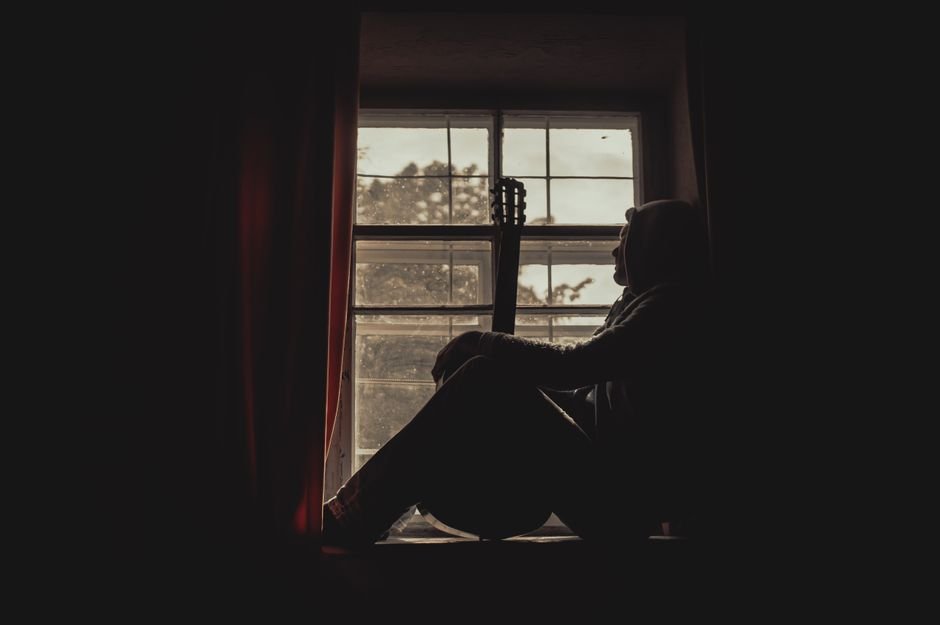 A person sitting alone by a window looking out
