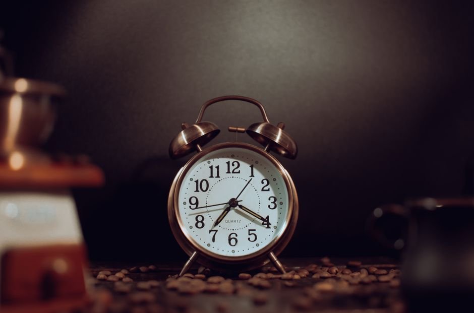 An alarm clock on a bedside table in a darkened bedroom