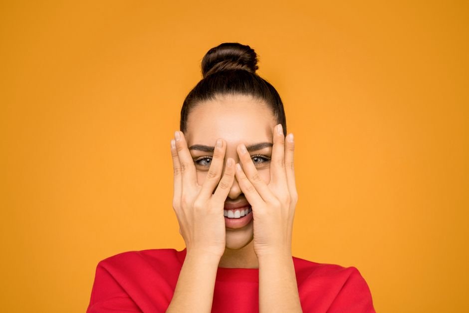 A woman shielding her eyes from bright light with one forearm