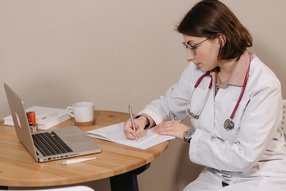 A clinician writing notes at a desk with a prescription pad