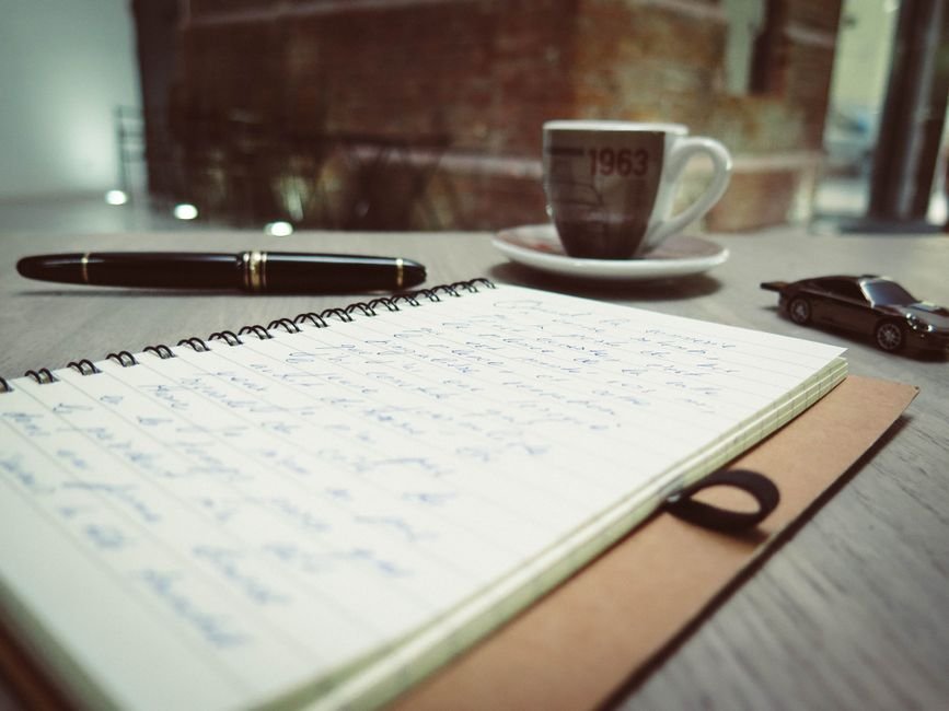An open notebook and pen on a desk with handwritten dated entries