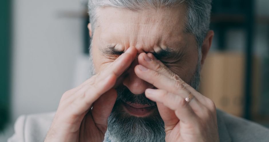 An older man pressing the fingers of one hand against his temple