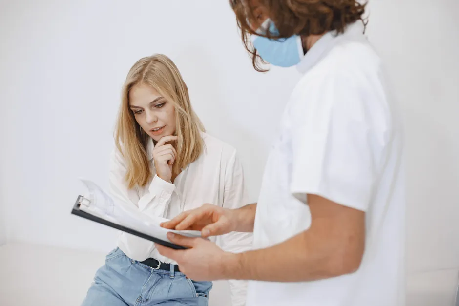 A clinician pointing to a written plan on a clipboard while a patient reads through her treatment options.